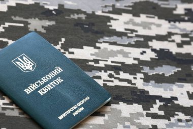 Piksel kamuflaj dokusuna sahip kumaş üzerinde Ukrayna askeri kimliği. Gri, kahverengi ve yeşil pikselli kamuflaj desenli kumaş Ukrayna ordusunun kişisel jetonuyla yakın plan..