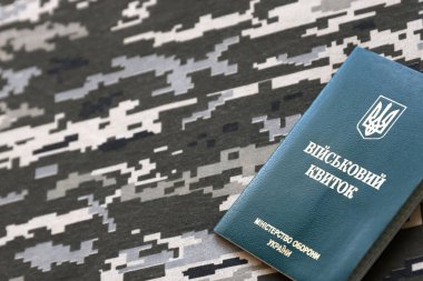 Piksel kamuflaj dokusuna sahip kumaş üzerinde Ukrayna askeri kimliği. Gri, kahverengi ve yeşil pikselli kamuflaj desenli kumaş Ukrayna ordusunun kişisel jetonuyla yakın plan..