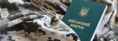 Piksel kamuflaj dokusuna sahip kumaş üzerinde Ukrayna askeri kimliği. Gri, kahverengi ve yeşil pikselli kamuflaj desenli kumaş Ukrayna ordusunun kişisel jetonuyla yakın plan..