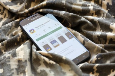 TERNOPIL, UKRAINE - 24 Nisan 2022: Askeri kamuflaj üniformasında akıllı telefon ekranında cep telefonu için Hava Baskını Siren uygulaması