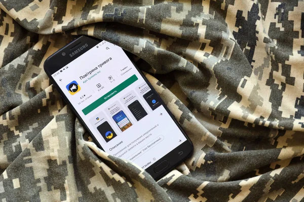 TERNOPIL, UKRAINE - 24 Nisan 2022: Askeri kamuflaj üniformasında akıllı telefon ekranında cep telefonu için Hava Baskını Siren uygulaması