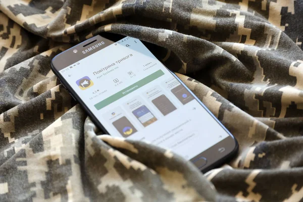 TERNOPIL, UKRAINE - 24 Nisan 2022: Askeri kamuflaj üniformasında akıllı telefon ekranında cep telefonu için Hava Baskını Siren uygulaması