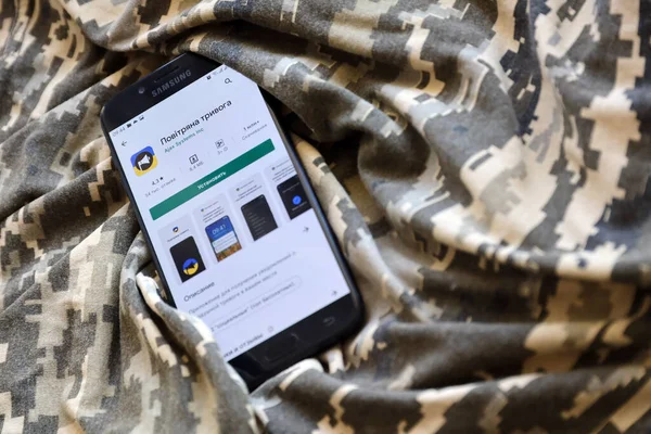 TERNOPIL, UKRAINE - 24 Nisan 2022: Askeri kamuflaj üniformasında akıllı telefon ekranında cep telefonu için Hava Baskını Siren uygulaması