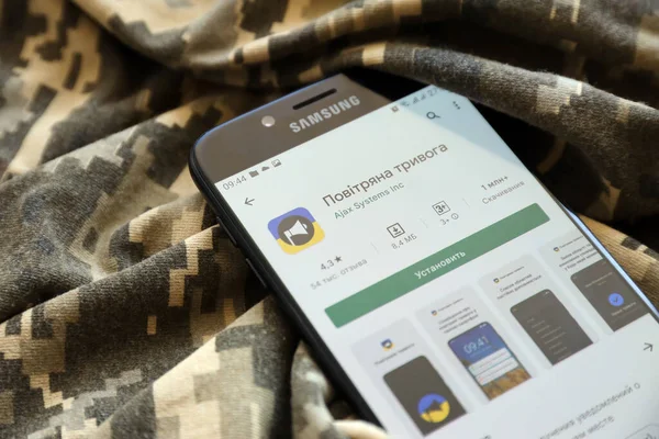 TERNOPIL, UKRAINE - 24 Nisan 2022: Askeri kamuflaj üniformasında akıllı telefon ekranında cep telefonu için Hava Baskını Siren uygulaması