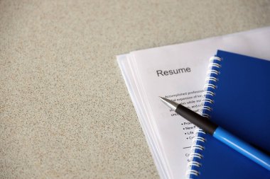 Top view of stack of office documents including resume and cv forms on the desk close to pen and notepad. Job seeking process. Hunting for workplace concept
