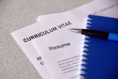 Top view of stack of office documents including resume and cv forms on the desk close to pen and notepad. Job seeking process. Hunting for workplace concept