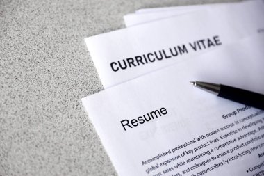 Top view of stack of office documents including resume and cv forms on the desk close to pen. Job seeking process. Hunting for workplace concept