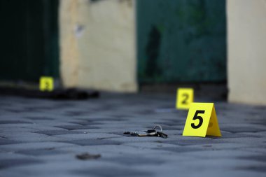 Evidence with yellow CSI marker for evidence numbering on the residental backyard in evening. Crime scene investigation process concept