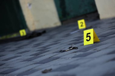 Evidence with yellow CSI marker for evidence numbering on the residental backyard in evening. Crime scene investigation process concept