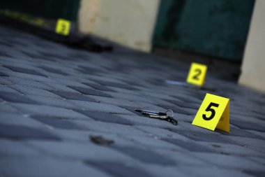 Evidence with yellow CSI marker for evidence numbering on the residental backyard in evening. Crime scene investigation process concept