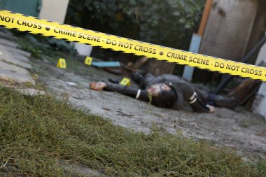 Akşamları bir rezidans evinin arka bahçesinde işlenen şiddet suçunun kurbanı. Sarı polis şeridinin altında ölü bir adam cesedi ve olay yerinde kanıt işaretleri var.