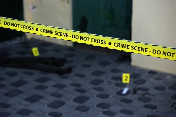 Crime scene tape for covering the area cordon. Yellow tape with blurred forensic law enforcement background in cinematic tone and copy space