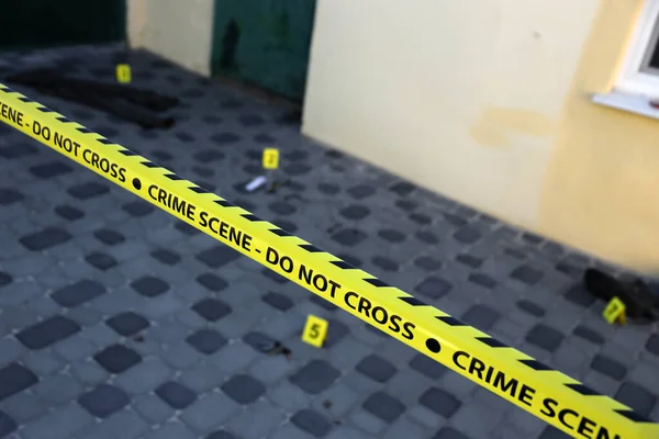 Crime scene tape for covering the area cordon. Yellow tape with blurred forensic law enforcement background in cinematic tone and copy space