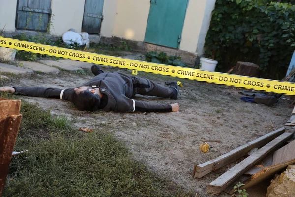 Akşamları bir rezidans evinin arka bahçesinde işlenen şiddet suçunun kurbanı. Sarı polis şeridinin altında ölü bir adam cesedi ve olay yerinde kanıt işaretleri var.