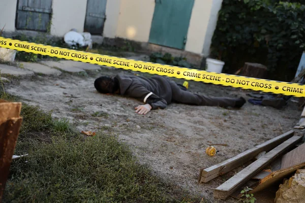 Akşamları bir rezidans evinin arka bahçesinde işlenen şiddet suçunun kurbanı. Sarı polis şeridinin altında ölü bir adam cesedi ve olay yerinde kanıt işaretleri var.