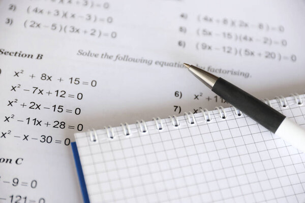 Handwriting of mathematics quadratic equation on examination, practice, quiz or test in maths class. Solving exponential equations background concept.