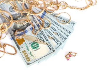 Birçok pahalı altın mücevher yüzük, küpeler ve beyaz arka planda büyük miktarda Amerikan doları banknotları olan kolyeler. Rehinci ya da kuyumcu konsepti.