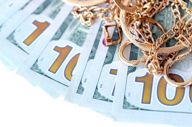 Birçok pahalı altın mücevher yüzük, küpeler ve beyaz arka planda büyük miktarda Amerikan doları banknotları olan kolyeler. Rehinci ya da kuyumcu konsepti.