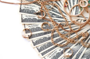 Birçok pahalı altın mücevher yüzük, küpeler ve beyaz arka planda büyük miktarda Amerikan doları banknotları olan kolyeler. Rehinci ya da kuyumcu konsepti.