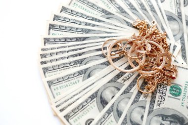 Birçok pahalı altın mücevher yüzük, küpeler ve beyaz arka planda büyük miktarda Amerikan doları banknotları olan kolyeler. Rehinci ya da kuyumcu konsepti.