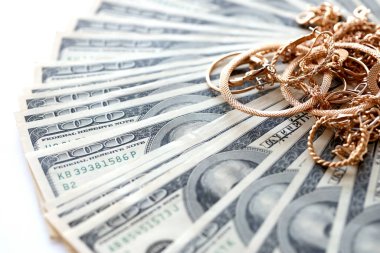 Birçok pahalı altın mücevher yüzük, küpeler ve beyaz arka planda büyük miktarda Amerikan doları banknotları olan kolyeler. Rehinci ya da kuyumcu konsepti.