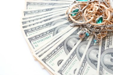 Birçok pahalı altın ve gümüş mücevher yüzük, küpe ve kolye beyaz arka planda büyük miktarda Amerikan doları var. Rehinci ya da kuyumcu konsepti.