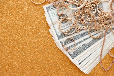 Pahalı altın mücevher yüzükler, küpeler ve lüks altın arka plan yüzeyi üzerine yüklü Amerikan dolarları olan kolyeler. Rehinci ya da kuyumcu konsepti.