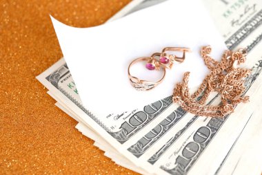 Pahalı altın mücevher yüzük, küpeler ve lüks altın arka planda pahalı Amerikan dolarları olan kolye. Rehinci ya da kuyumcu konsepti.