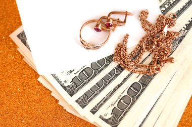 Pahalı altın mücevher yüzük, küpeler ve lüks altın arka planda pahalı Amerikan dolarları olan kolye. Rehinci ya da kuyumcu konsepti.