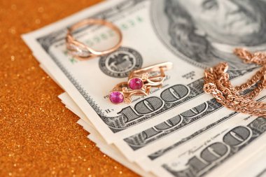 Pahalı altın mücevher yüzük, küpeler ve lüks altın arka planda pahalı Amerikan dolarları olan kolye. Rehinci ya da kuyumcu konsepti.