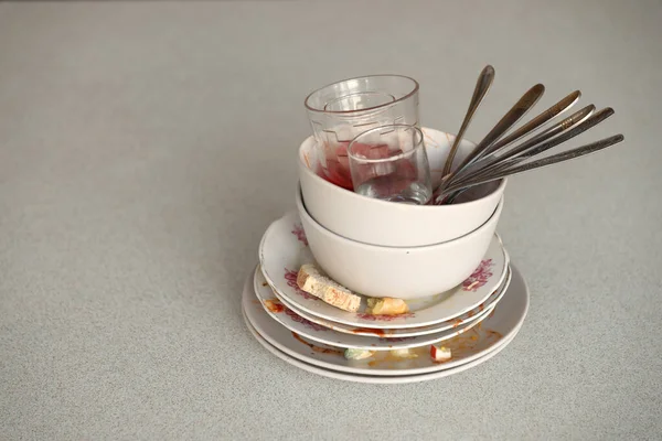 Stack of dirty dishes with food leftovers on the table after meal. Banquet ending concept. Unwashed dishes ready to cleaning