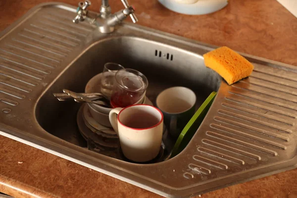 Stack of dirty dishes with food leftovers in the kitchen sink. Unwashed dishes ready to cleaning