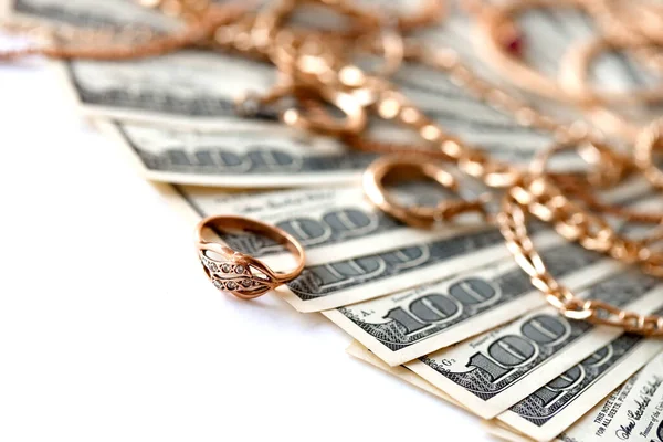 Birçok pahalı altın mücevher yüzük, küpeler ve beyaz arka planda büyük miktarda Amerikan doları banknotları olan kolyeler. Rehinci ya da kuyumcu konsepti.