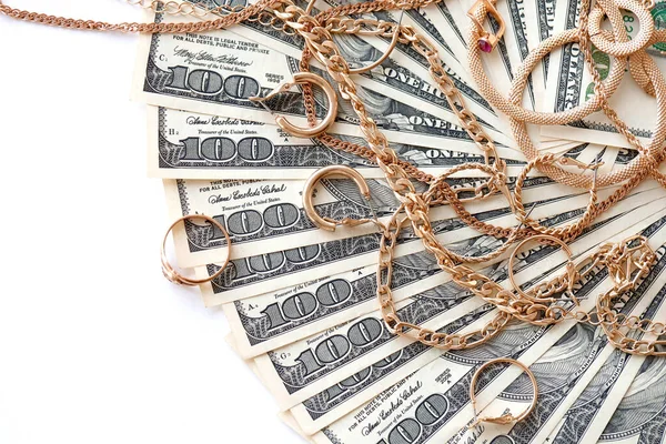 Birçok pahalı altın mücevher yüzük, küpeler ve beyaz arka planda büyük miktarda Amerikan doları banknotları olan kolyeler. Rehinci ya da kuyumcu konsepti.