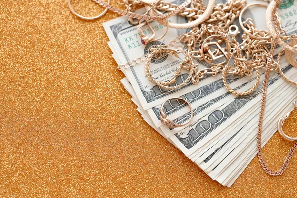 许多昂贵的金光闪闪的珠宝戒指 耳环和项链 其奢华的金光闪闪的背景表面上印有大量的美元钞票 当铺或珠宝店的概念 — 图库照片