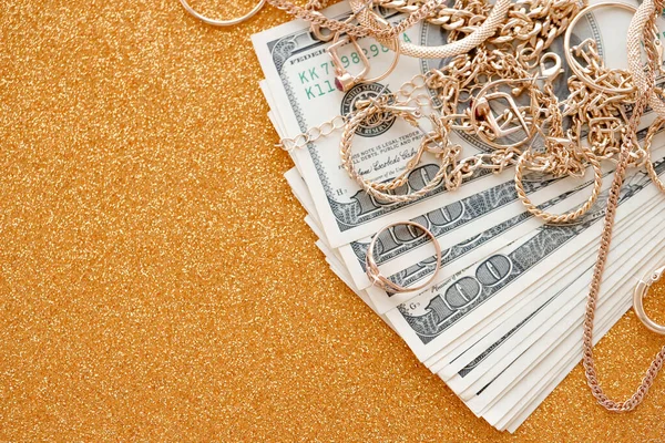 Pahalı altın mücevher yüzükler, küpeler ve lüks altın arka plan yüzeyi üzerine yüklü Amerikan dolarları olan kolyeler. Rehinci ya da kuyumcu konsepti.