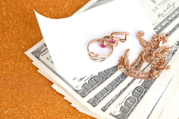 Pahalı altın mücevher yüzük, küpeler ve lüks altın arka planda pahalı Amerikan dolarları olan kolye. Rehinci ya da kuyumcu konsepti.