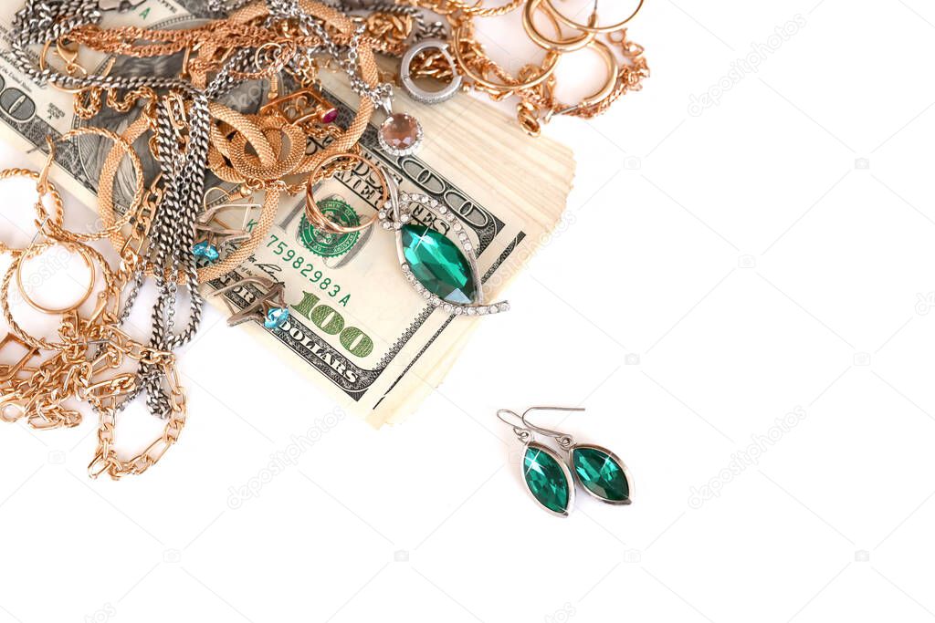 Many expensive golden and silver jewerly rings, earrings and necklaces with big amount of US dollar bills on white background. Pawnshop or jewerly shop concept