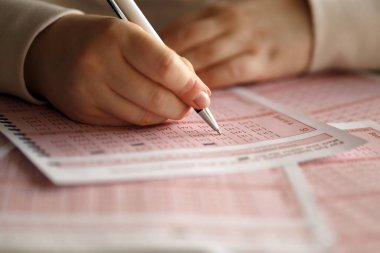 Piyango bileti dolduruyorum. Genç bir kadın piyango oynar ve büyük ikramiyeyi kazanmayı hayal eder. Kırmızı piyango biletindeki kadın el işareti numarası. Yakın çekim.