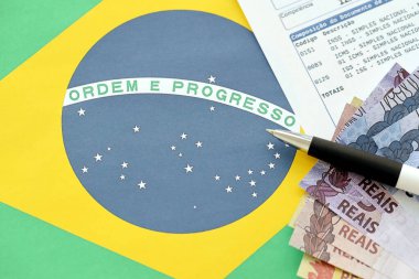 TERNOPIL, UKRAINE - 20 Mayıs 2022: Brezilya tahsilat raporunun Brezilya reel paraları ve ulusal bayrak arka planında kalem ile kanıtlanması. Brezilya 'nın yasal vergi ödeme ve vergi raporlama kavramı