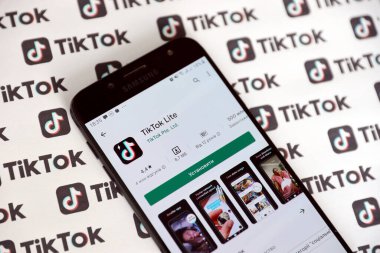 TERNOPIL, UKRAINE - 2 Mayıs 2022: Tik Tok akıllı telefon uygulaması ekranda ve birçok TikTok logosu kağıda basıldı. Tiktok veya Douyin, ByteDance Ltd. 'nin sahibi olduğu Çin yapımı kısa formatlı video sunucu servisidir.