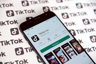 TERNOPIL, UKRAINE - 2 Mayıs 2022: Tik Tok akıllı telefon uygulaması ekranda ve birçok TikTok logosu kağıda basıldı. Tiktok veya Douyin, ByteDance Ltd. 'nin sahibi olduğu Çin yapımı kısa formatlı video sunucu servisidir.