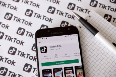 TERNOPIL, UKRAINE - 2 Mayıs 2022: Tik Tok akıllı telefon uygulaması ekranda ve birçok TikTok logosu kağıda basıldı. Tiktok veya Douyin, ByteDance Ltd. 'nin sahibi olduğu Çin yapımı kısa formatlı video sunucu servisidir.