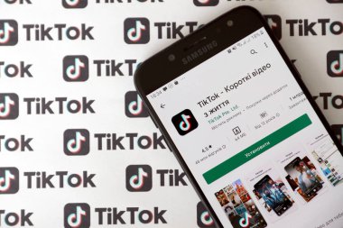 TERNOPIL, UKRAINE - 2 Mayıs 2022: Tik Tok akıllı telefon uygulaması ekranda ve birçok TikTok logosu kağıda basıldı. Tiktok veya Douyin, ByteDance Ltd. 'nin sahibi olduğu Çin yapımı kısa formatlı video sunucu servisidir.