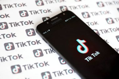 TERNOPIL, UKRAINE - 2 Mayıs 2022: Tik Tok akıllı telefon uygulaması ekranda ve birçok TikTok logosu kağıda basıldı. Tiktok veya Douyin, ByteDance Ltd. 'nin sahibi olduğu Çin yapımı kısa formatlı video sunucu servisidir.
