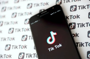 TERNOPIL, UKRAINE - 2 Mayıs 2022: Tik Tok akıllı telefon uygulaması ekranda ve birçok TikTok logosu kağıda basıldı. Tiktok veya Douyin, ByteDance Ltd. 'nin sahibi olduğu Çin yapımı kısa formatlı video sunucu servisidir.