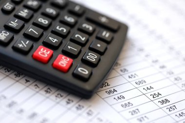 Büyük siyah hesap makinesi mali tablolarda ve bilançoda denetçinin masasında yatıyor. Muhasebe ve denetim işleri kavramı. Vergi ödeyen ve çalışan işler