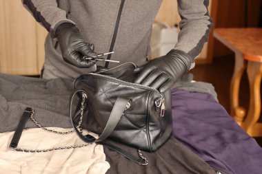 Siyah kıyafetli ve eldivenli soyguncu, çalıntı kadın çantasının içini görmüş. Hırsız, mutfaktaki bir kadın çantasından evin anahtarlarını almış.