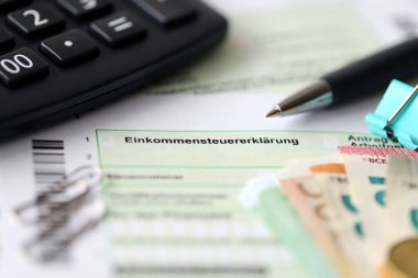 Kalem ve avrupa para faturalarıyla birlikte Alman gelir vergisi iadesi formu muhasebeci masasına yakın duruyor. Almanya 'daki vergi mükellefleri, vergi ödemek için ana para birimi olarak avro para kullanıyorlar