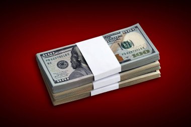 Kırmızı arka planda bir deste Amerikan doları banknotları. Koyu kırmızı arka planda yüksek çözünürlüklü bir paket Amerikan parası.
